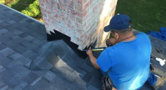 man repairing roof seal around a chimney