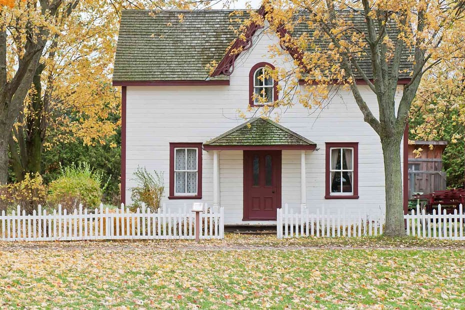 a white home surrounded by fall leaves