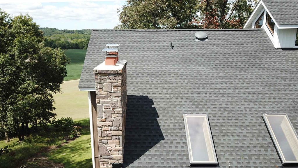 Maryland home roof with skylights and a chimney installed by American Home Contractors your Maryland roofer