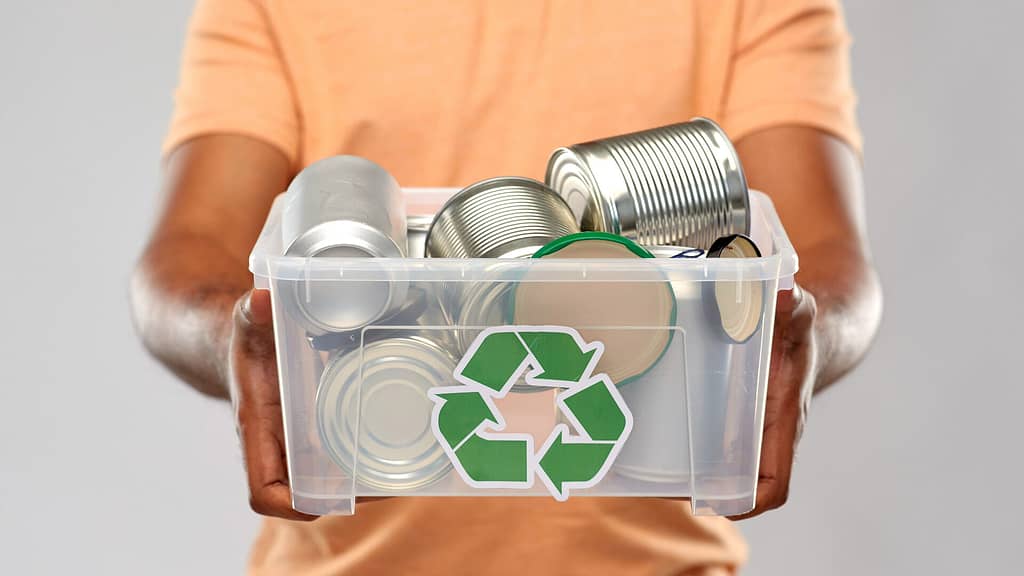 person holding a tin can containers for recycling