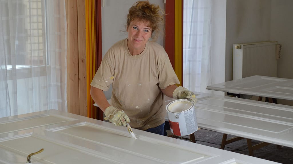 smiling person painting a door