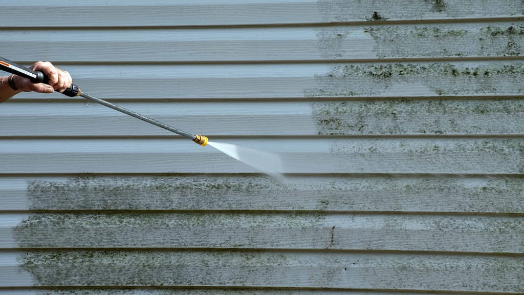 person cleaning a vinyl siding