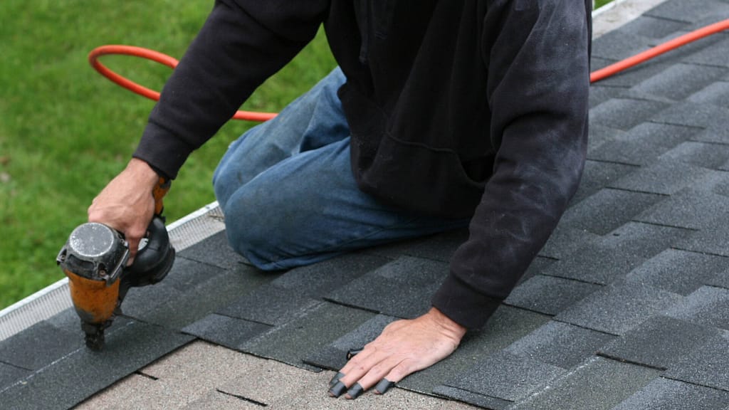 person installing missing shingles on a roof