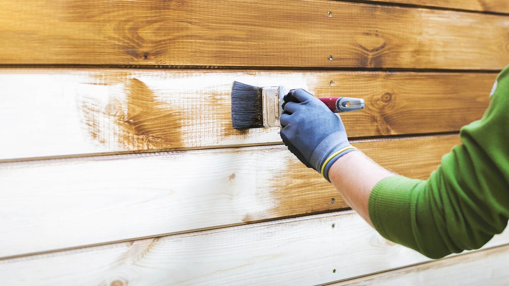 person painting a wooden siding