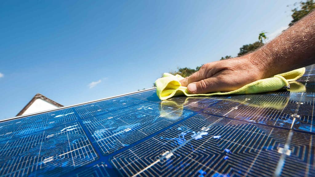 person cleaning solar panel on roof