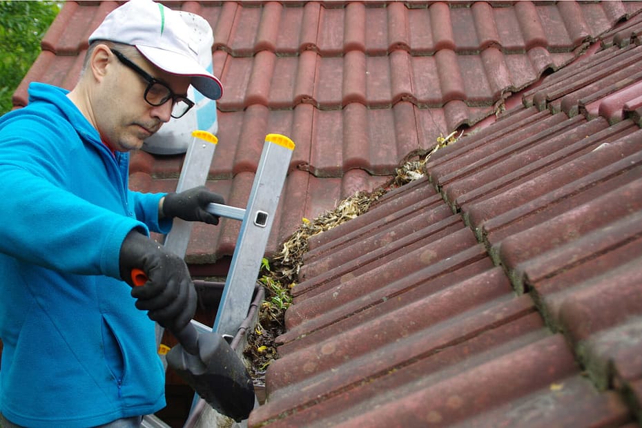 Person cleaning gutter using gutter scoop